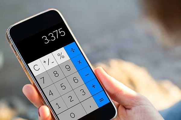 A person’s hand holds a calculator with a digital display. The display’s buttons are blue down the right side, white across the top, and a grey block between them. The readout shows a number: 3.375. 