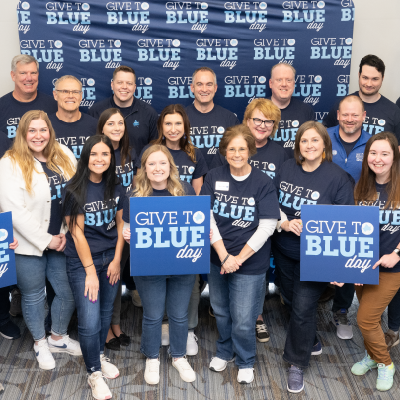 Staff holding Give to Blue Day signs