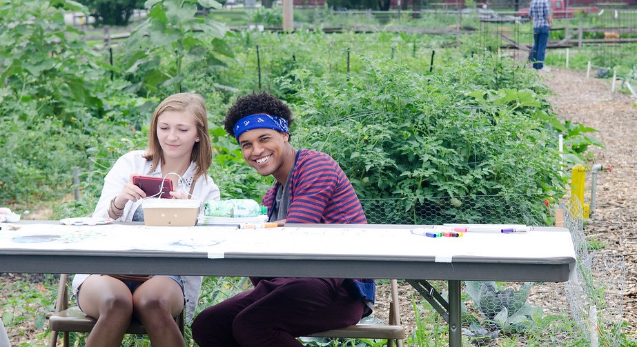 Students at a table in front of the community garden